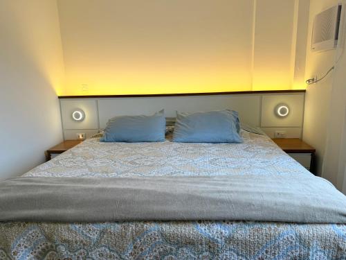 a bedroom with a bed with two blue pillows at Lar e Mar PG in Praia Grande
