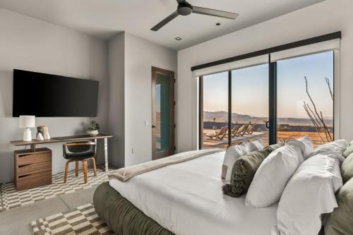 a bedroom with a large bed with a flat screen tv at Sunstill by Fieldtrip Modern w Custom Pool Spa Views in Joshua Tree