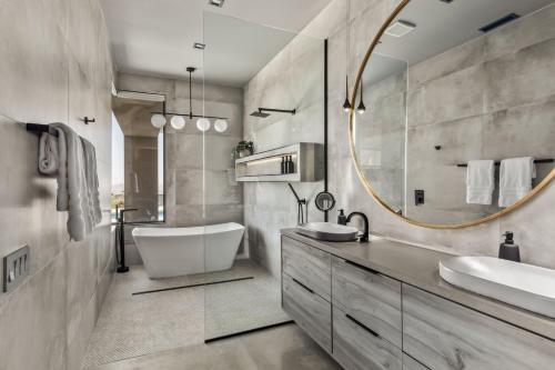 a bathroom with a tub and a sink and a mirror at Sunstill by Fieldtrip Modern w Custom Pool Spa Views in Joshua Tree