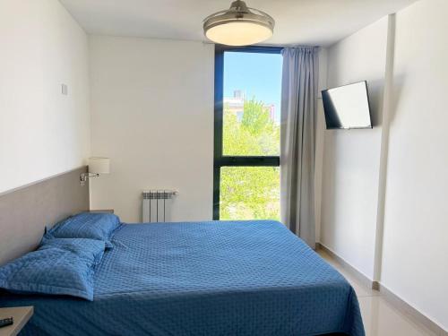 una camera da letto con un letto blu e una finestra di Vow a Villa Carlos Paz