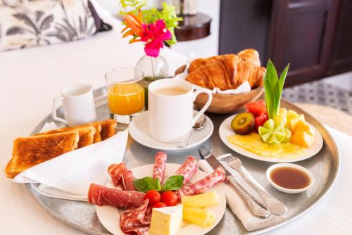 een ontbijtplateau met ontbijtproducten en koffie op een tafel bij Villa Marie - Habitation Saint Charles in Petit-Bourg