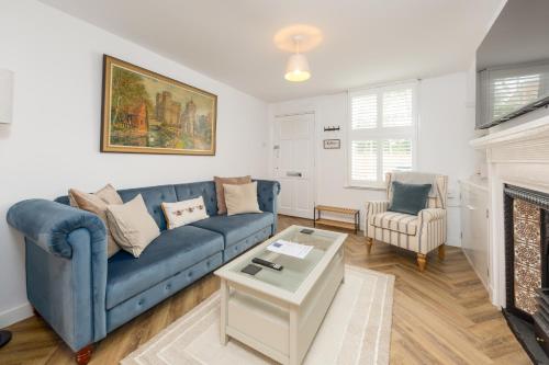 a living room with a blue couch and a fireplace at Rose cottage, Central, Amazing Cathedral view, Iconic pastel street in Canterbury
