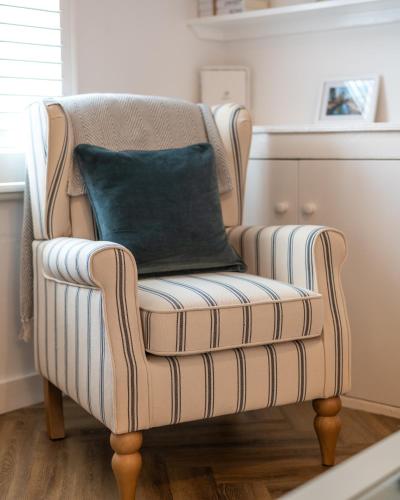 a striped chair with a blue pillow on it at Rose cottage, Central, Amazing Cathedral view, Iconic pastel street in Canterbury