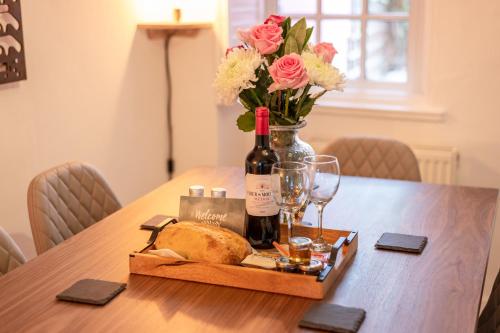 a table with a bottle of wine and a loaf of bread and flowers at Rose cottage, Central, Amazing Cathedral view, Iconic pastel street in Canterbury