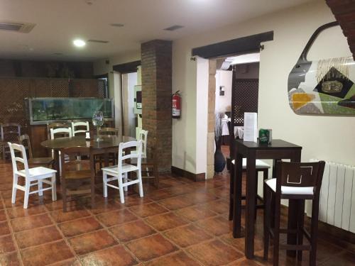 a dining room with tables and white chairs at Hotel Marfrei in Hinojedo