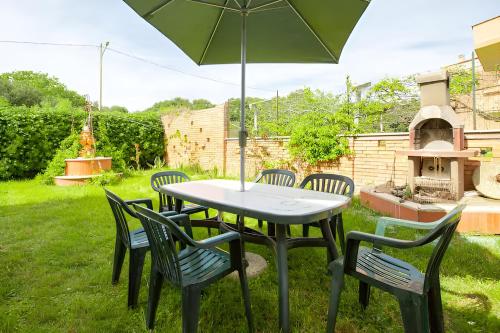 a table and chairs with an umbrella in a yard at VILLA LILLA Beachfront - Sea View with Parking and Private Garden in Anzio