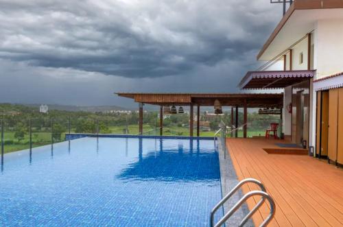 a swimming pool with a view of a house at The Tanisi Resorts & Pool Villas, Candolim in Candolim