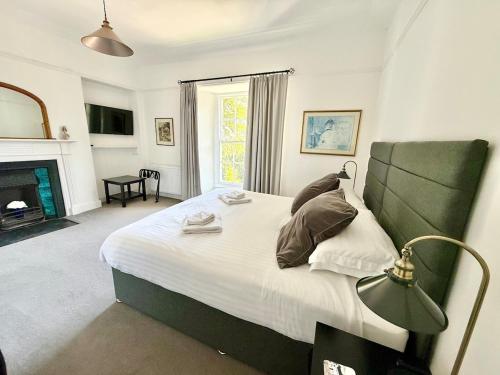 a bedroom with a large bed and a fireplace at A Grand Georgian Grade II Manor House with Views in Laugharne in Laugharne