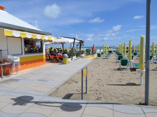 a beach with a restaurant and chairs on the sand at Daina Residence in Lido di Jesolo