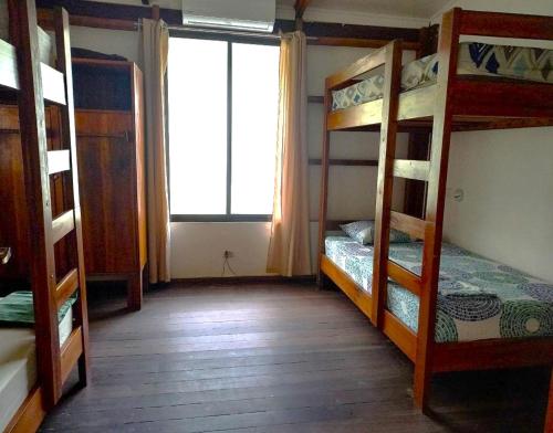 a room with three bunk beds and a window at Pagalù Hostel in Puerto Viejo