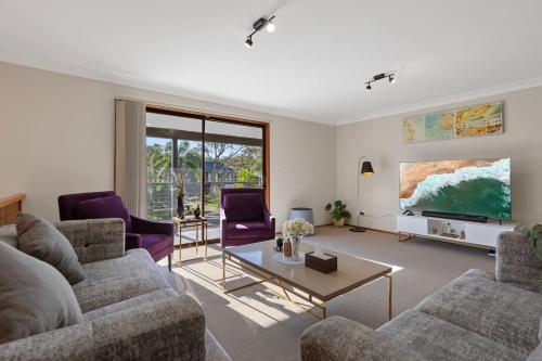 a living room with two couches and a tv at San Remo Charm with Waterfront Views and Sunroom in Blue Haven