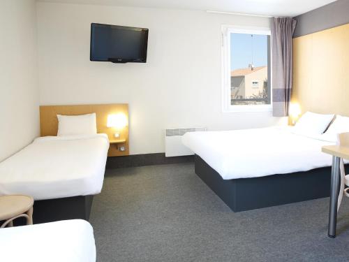 a hotel room with two beds and a tv at B&B HOTEL Marseille Aéroport Saint-Victoret in Saint-Victoret