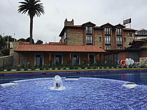 a fountain in the middle of a pool in front of a house at Hotel Marfrei in Hinojedo