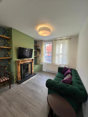 a living room with a green couch and a fireplace at Hartoft House, 3 Bed, Near River and City in York