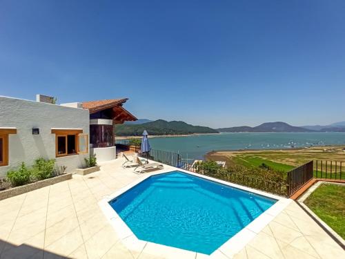 a villa with a swimming pool and a view of the water at Rustic house with stunning lake view in Valle de Bravo