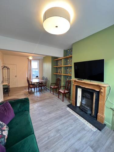 a living room with a green couch and a fireplace at Hartoft House, 3 Bed, Near River and City in York