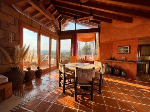 a dining room with a table and chairs and windows at Rustic house with stunning lake view in Valle de Bravo