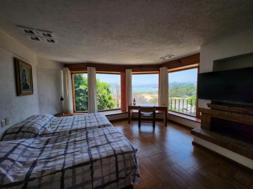 een slaapkamer met een bed en een groot raam bij Rustic house with stunning lake view in Valle de Bravo