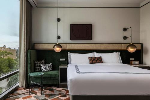 a bedroom with a large bed and a green chair at The Tess, Autograph Collection in Atlanta