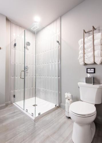 a white bathroom with a shower and a toilet at Hollyhock Suite 503 in Louisville
