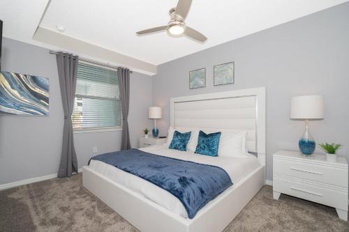 Un dormitorio blanco con una cama y un ventilador de techo. en 3111-102RD CONDO 2 BEDS/2 BATHS (SANITIZED), en Kissimmee