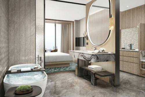 een badkamer met een bad, een bed en een wastafel bij The Westin Yichang in Yichang