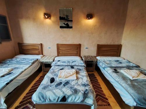 a room with three beds in a room at El Dorado Camp in Siwa