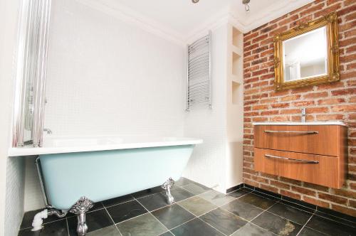 a bathroom with a white tub and a brick wall at Sillwood Balcony Apartment - Central - by Brighton Holiday Lets in Brighton & Hove