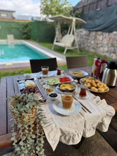 een tafel met eten en drinken naast een zwembad bij Bungarella Deluxe Bungalows in Sapanca