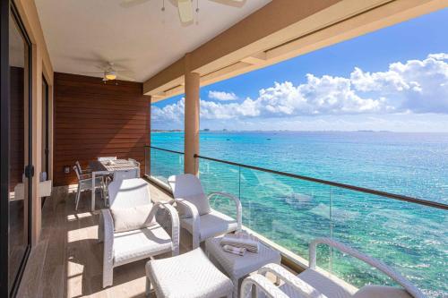 a balcony with white chairs and a view of the ocean at SeaDreams 8 - Luxury Condo with Shared Pool, Hot Tub, Rooftop Lounge in West Bay