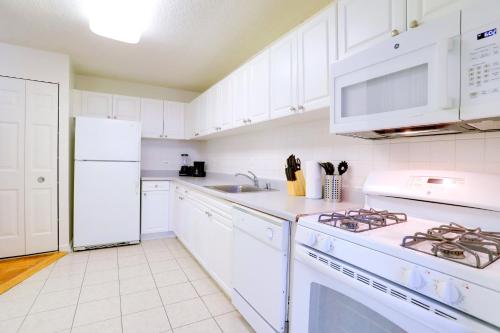 La cuisine est équipée de placards blancs et d'un four avec plaques de cuisson blanches. dans l'établissement Spacious Apt W Great Spaces & Facilities, à Addison Heights