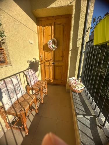 a porch with two chairs and a wooden door at Tavaszmező in Pécs