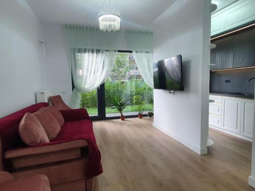 ein Wohnzimmer mit einem roten Sofa und einem TV in der Unterkunft White Silk - Premium Apartment with free underground parking in Iaşi