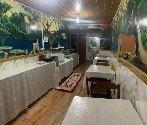 un restaurant avec des tables et une cuisine ornée d'une fresque dans l'établissement Hotel Raiz, à Manaus