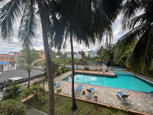 a swimming pool with palm trees and lounge chairs at Charming Apartment with Pool View Near the Beach in Flic-en-Flac