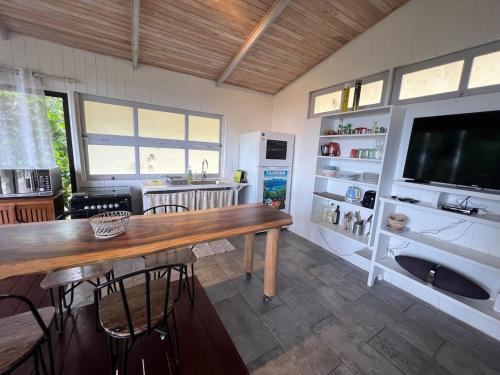 a living room with a large wooden table and a television at Charming bungalow with sea view facing Marina Taina in Punaauia