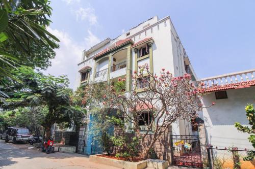 a white building with a tree in front of it at Hotel O Krupa Service Apartments in Hyderabad