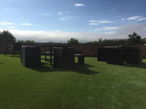 a park with tables and chairs on a grass field at Hotel Marfrei in Hinojedo