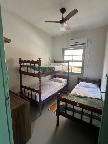 Una habitación con dos literas y un ventilador de techo. en Dragonfly Beach House Quatro Ilhas, en Bombinhas