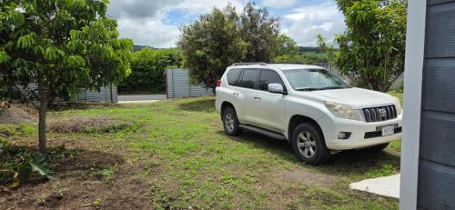 Una camioneta blanca estacionada en un patio junto a un árbol. en contenedor estudio, en Tilarán