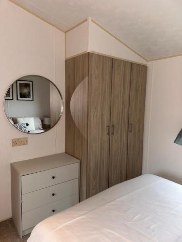 a bedroom with a wooden cabinet and a mirror at Two Bedroom Caravan on 7 Lakes Country Park in Crowle