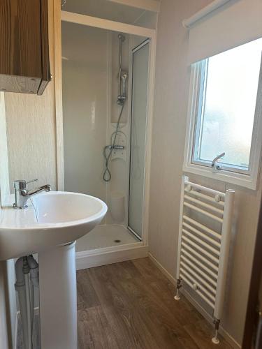 a bathroom with a white sink and a shower at Seawick Caravan 922 in Clacton-on-Sea