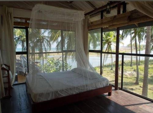 Un dormitorio con una cama en una habitación con ventanas. en Diyamba Beach Resort kalpitiya, en Kalpitiya