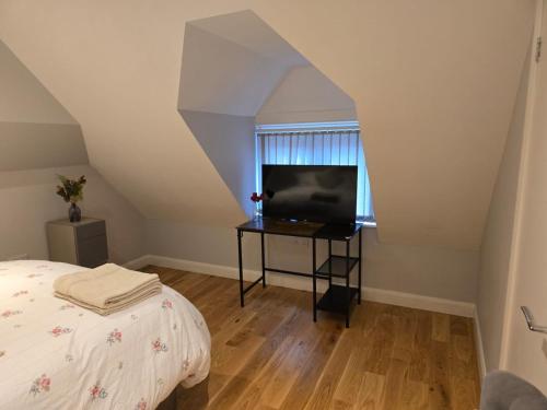 a bedroom with a bed and a desk with a television at MJ Rooms, St Leonads on Sea, Hastings UK in Hollington