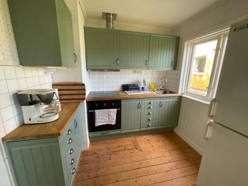 a small kitchen with green cabinets and a window at Charming cottage outside Norrköping in Åby
