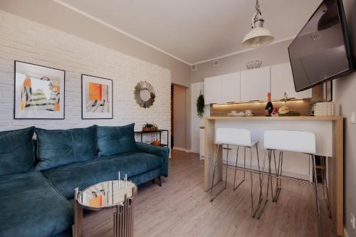 Una sala de estar con un sofá azul y una cocina. en Baltic 4YOU, en Pobierowo