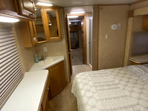 a small room with a bed and a sink and a bathroom at Platte-Camper in Woods w/FirePit & Hot Tub Access in Benzonia