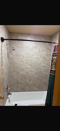 a bathroom with a bath tub and a shower curtain at Deluxe Inn in Hebron