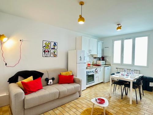 Una sala de estar con un sofá y una mesa y una cocina. en La Maison de Mickey - Disneyland Paris, en Bailly-Romainvilliers