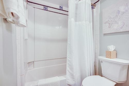 a bathroom with a white shower curtain and a toilet at Poolside Fun & Ocean Strolls: Harbor Island Haven! in Fripp Island